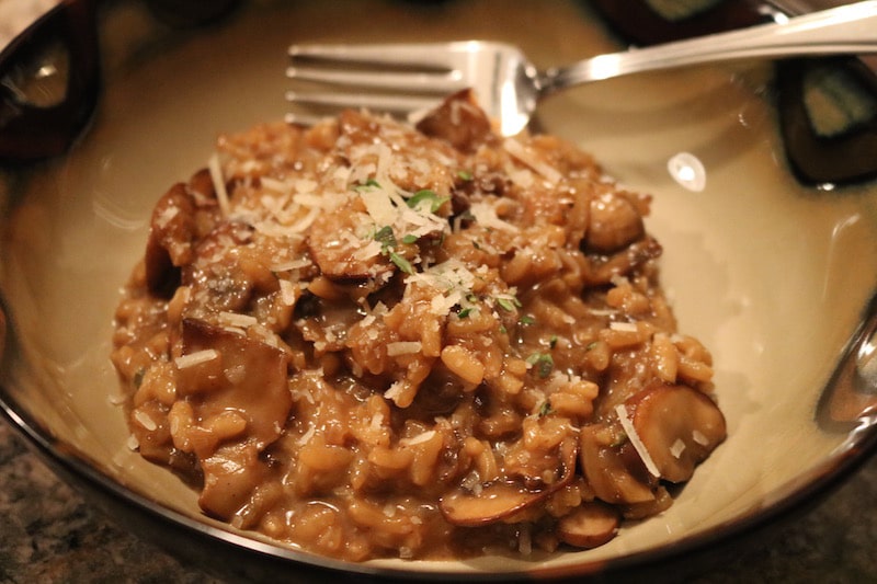 Close-up of a bowl of creamy mushroom risotto with a fork resting in the bowl.