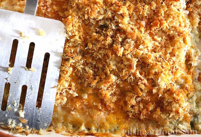 Close-up of the top of baked cod au gratin with a spatula resting on it.