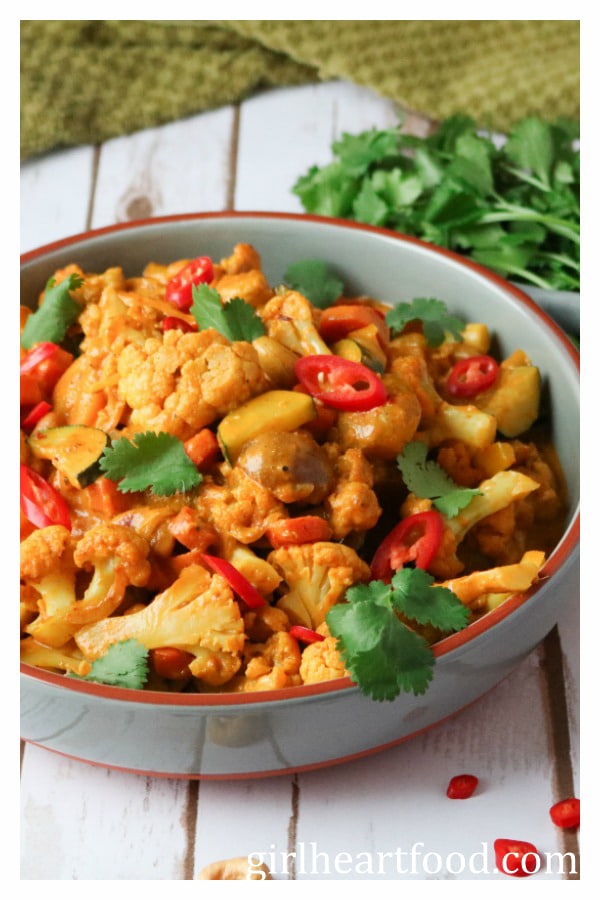 Vegetable korma in a dish with some fresh cilantro behind it.