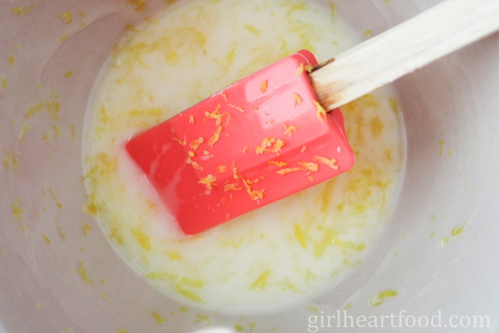 Stirring a lemon icing sugar glaze with a spatula.