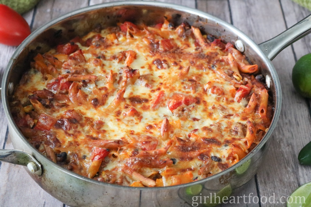 Cheesy pasta bake in a pan before being garnished with toppings.