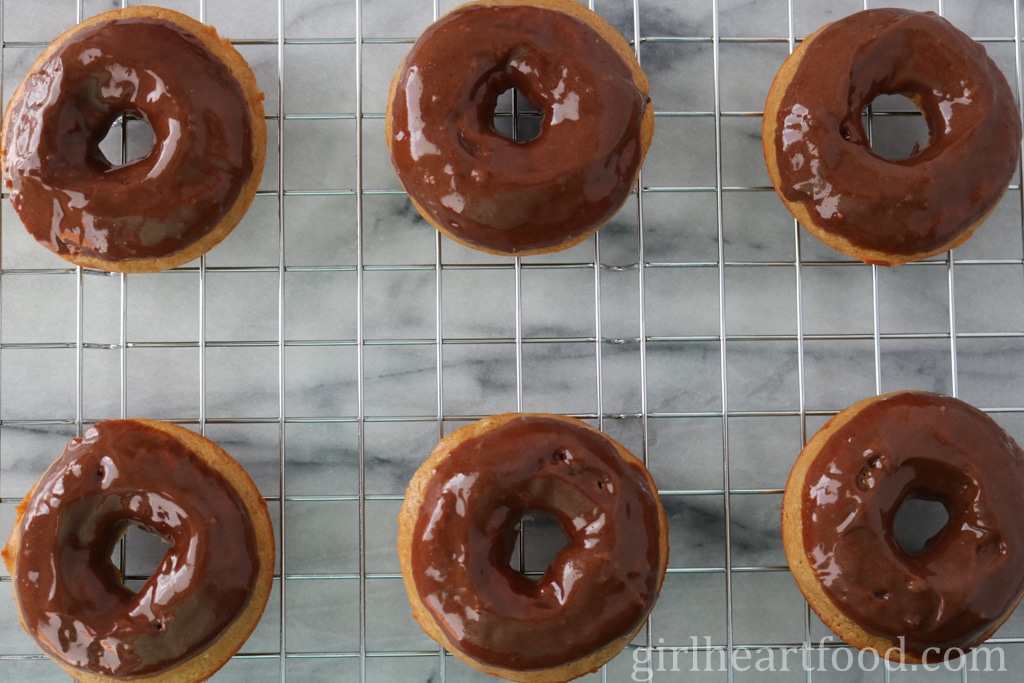 Six glazed donuts on a cooling rack.