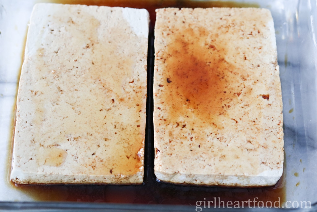 Two slabs of tofu in a dish being marinated.