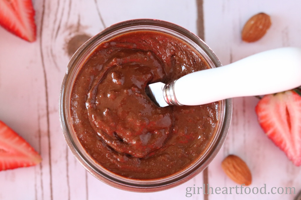 Jar of chocolate almond butter with a spreader dipped into it.