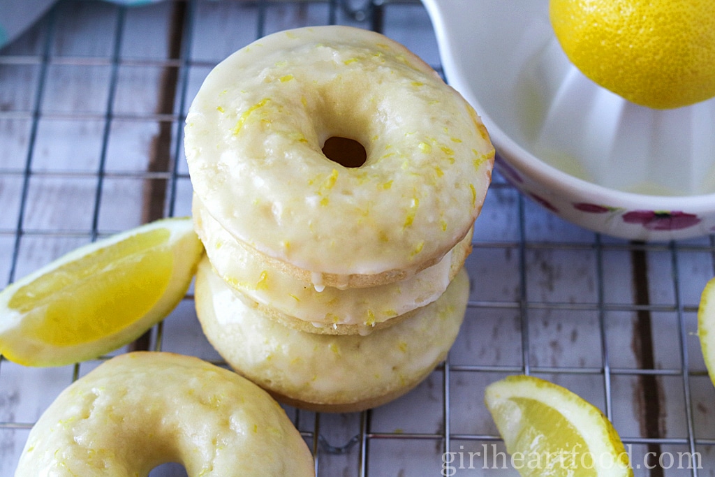 Stack of glazed coconut lemon donuts on a wire rack.
