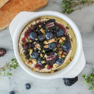 Dish of baked camembert topped with jam, berries, walnuts and thyme.