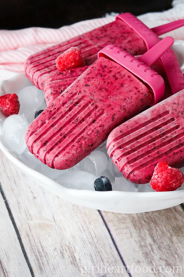 Frozen berry ice pops over ice in a bowl.