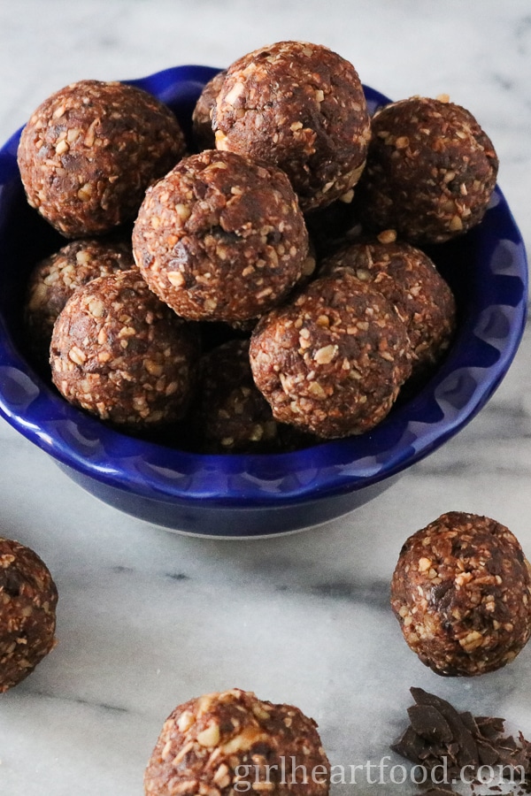 Chocolate coconut balls, some in a blue dish and some on a board.