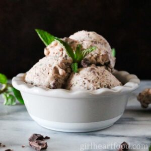 Scoops of mint chocolate banana ice cream with fresh mint in a bowl.