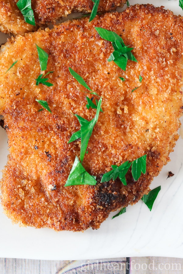 Close-up of a piece of pork schnitzel garnished with parsley.