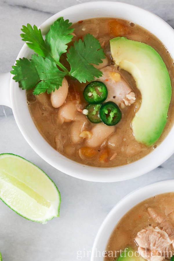 Two bowls of white chicken chili with toppings.