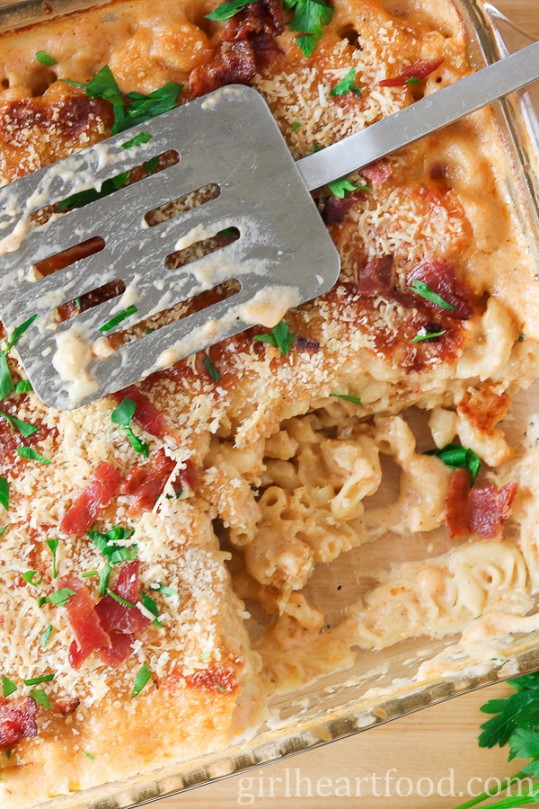 Baked mac and cheese in a baking dish with a spatula resting on top.