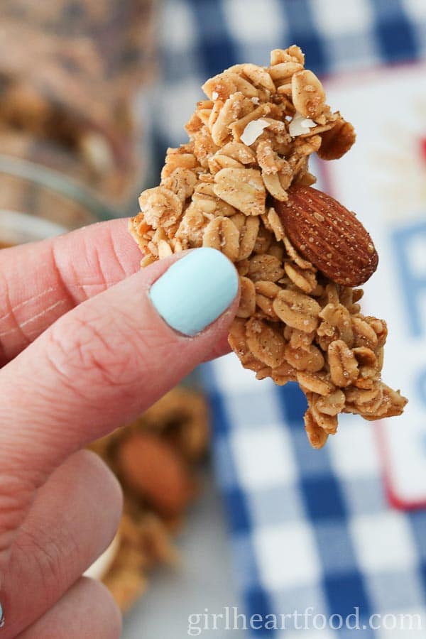 Hand holding a piece of clumpy homemade granola.