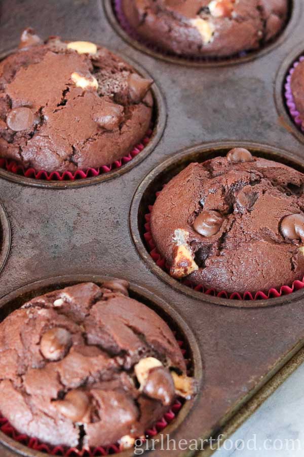 Baked triple chocolate muffins in a muffin pan.