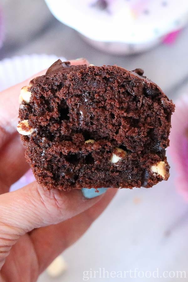 Hand holding half of a triple chocolate muffin.