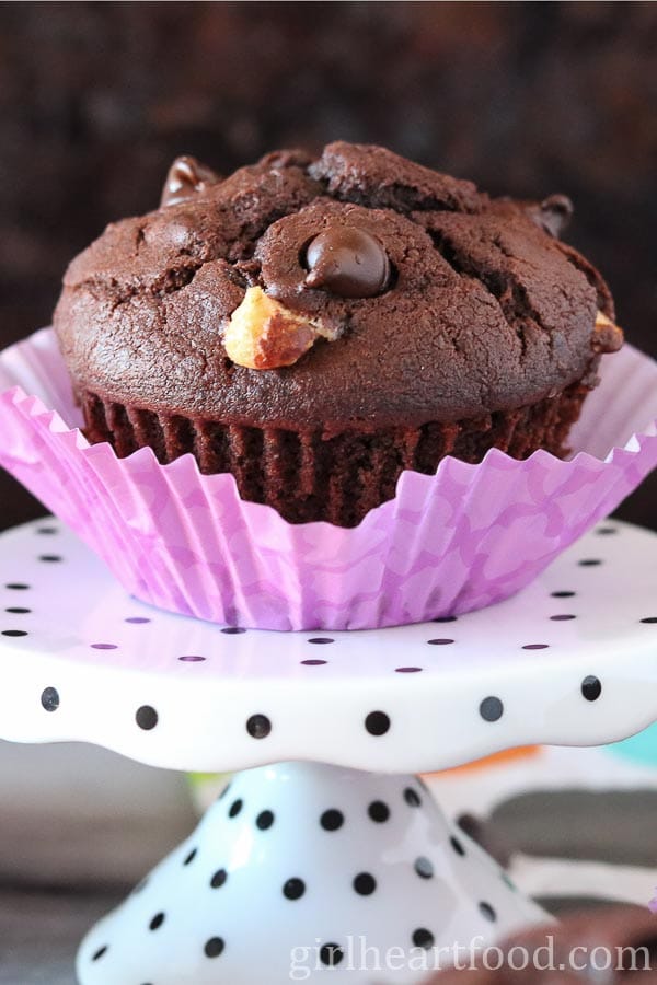 Triple chocolate muffin with purple liner on a polka dot stand.