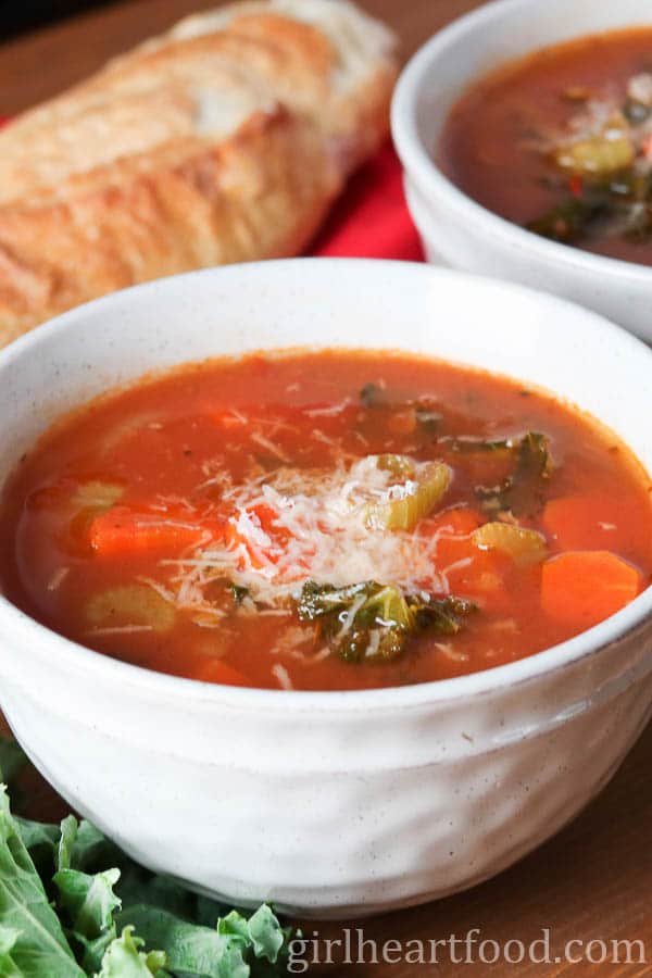 Bowl of lentil and kale soup garnished with parmesan cheese.