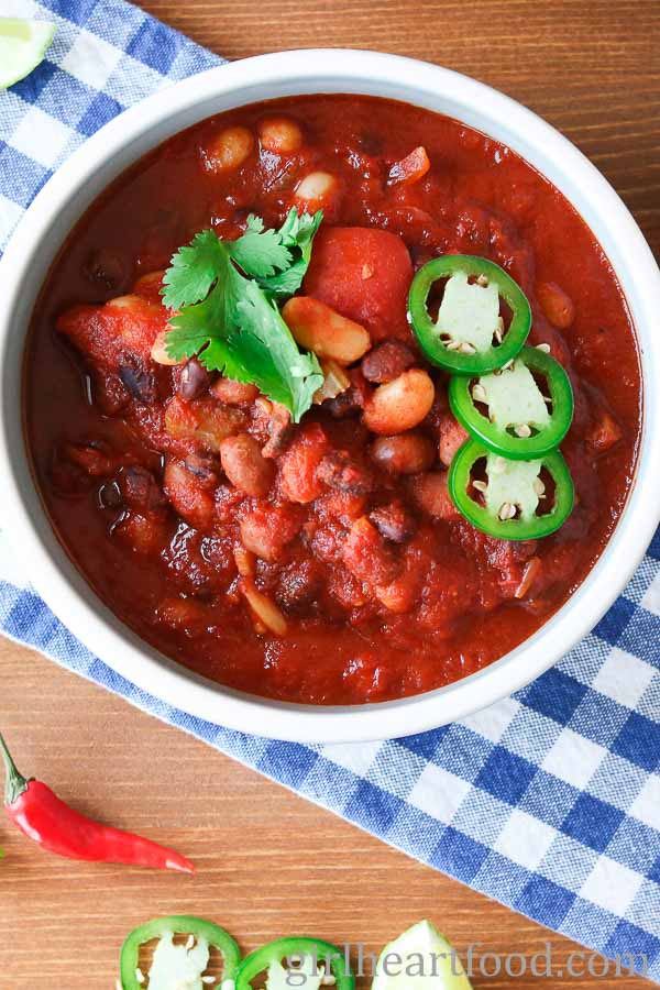 Bowl of three bean chili garnished with toppings.