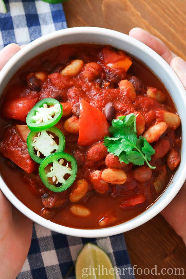 Two hands holding a bowl of three bean chili.