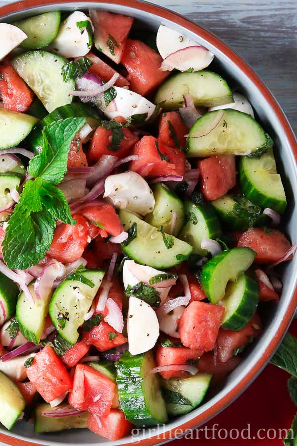 Close-up of a bowl of watermelon cucumber bocconcini salad with fresh mint.