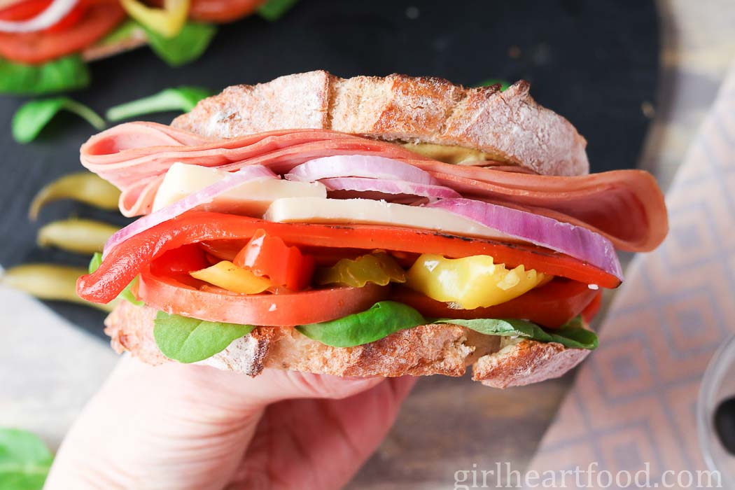 Hand met een broodje mortadella.