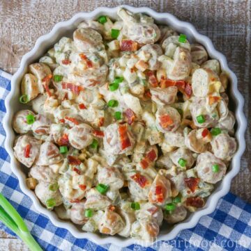 Chunky potato salad in a dish next to green onion.