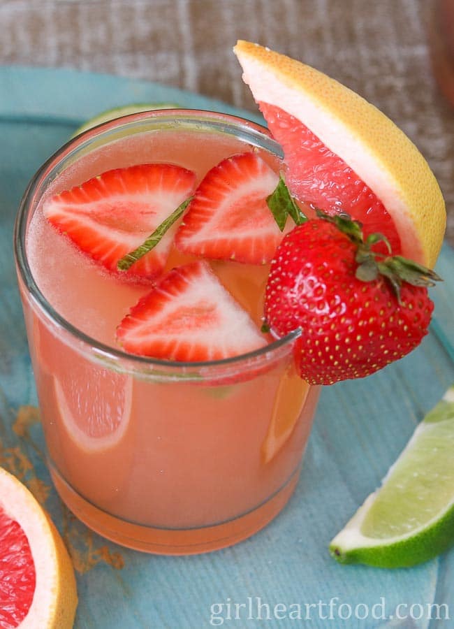 Close-up of a glass of grapefruit rosé sangria garnished with strawberry and grapefruit.