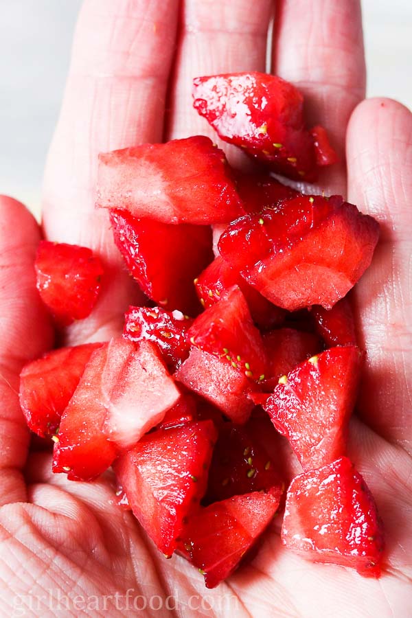 Hand holding chopped strawberries.