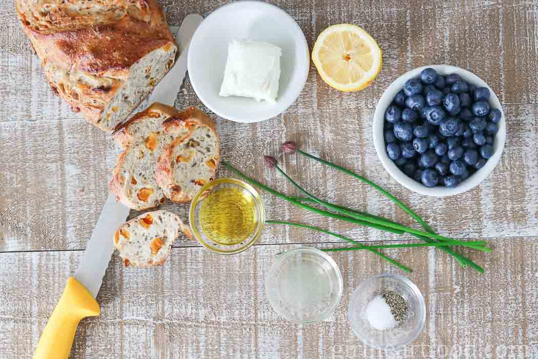 Ingredients for a roasted blueberry and goat cheese crostini recipe next to a knife.