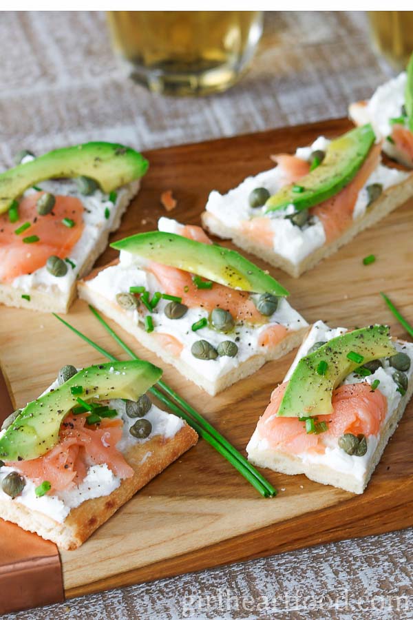 Portions of avocado and smoked salmon flatbread next to fresh chives.