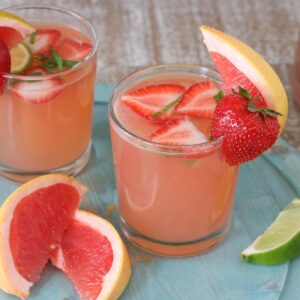 Two glasses of grapefruit rosé sangria, each garnished with a strawberry and grapefruit wedge.