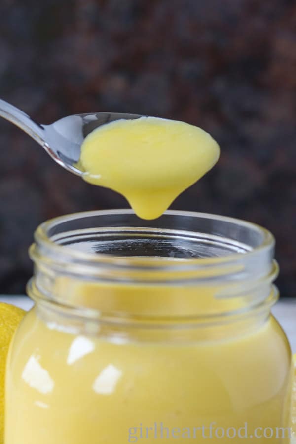 Spoonful of homemade lemon curd from a jar.