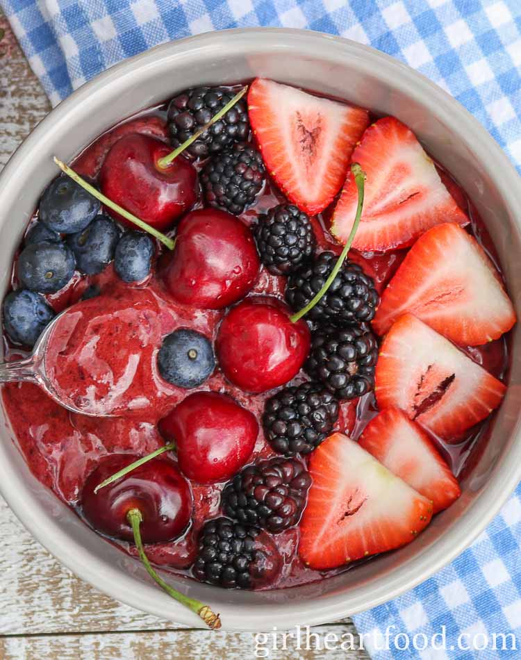 Fruit smoothie bowl garnished with lots of fresh berries and cherries.