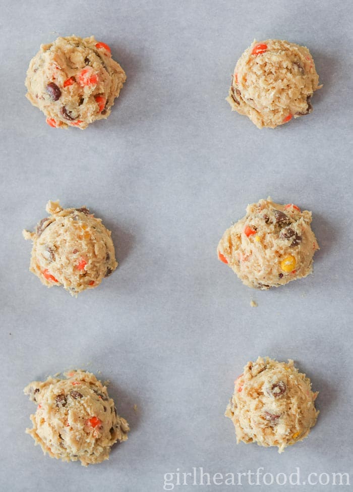 Raw cookies on a parchment paper-lined cookie sheet before being baked.