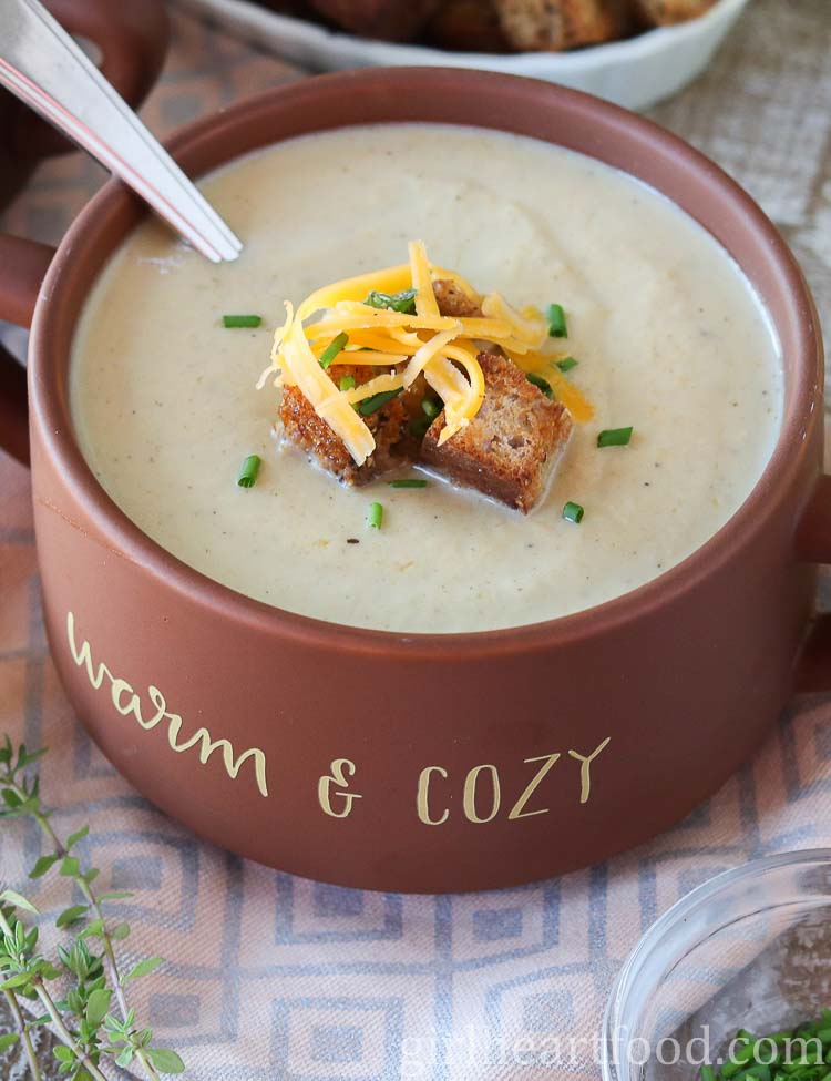 Bowl of creamy cauliflower leek soup garnished with croutons, chives and cheddar.