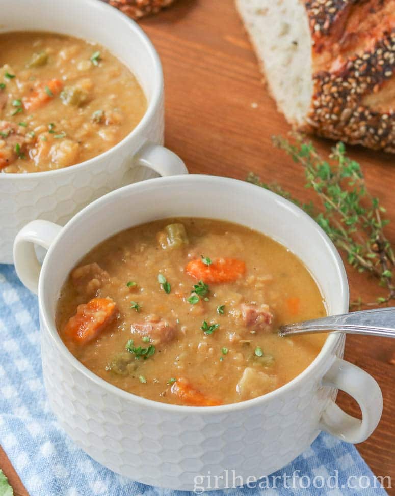 Two bowls of split pea and ham soup, one bowl in front of the other.