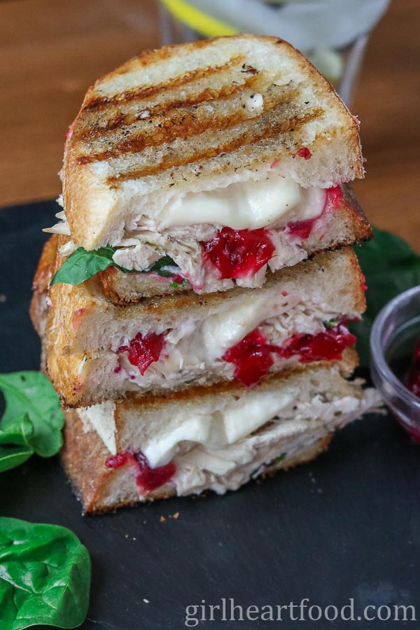 Stack of three cheesy turkey cranberry sandwich halves.