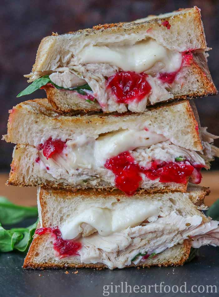 Close-up of a stack of three cheesy turkey cranberry sandwich halves.