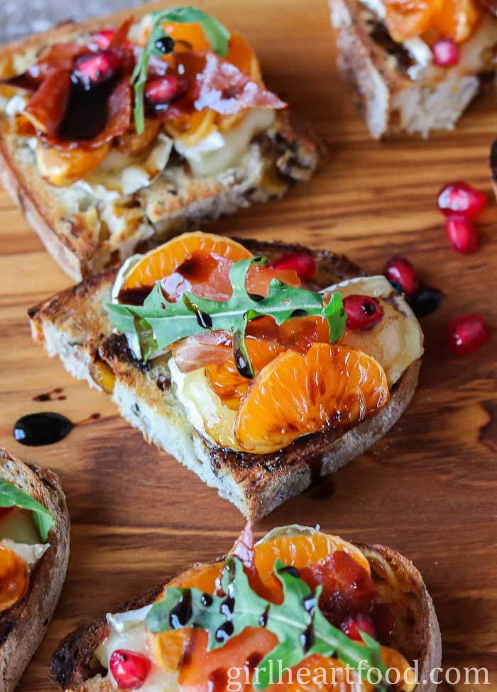 Close-up of a crostini with clementine, Brie, prosciutto, arugula and balsamic.