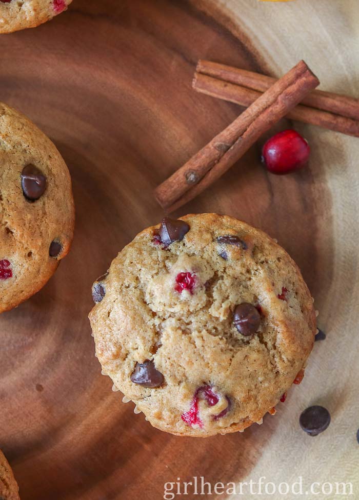 Cranberry orange chocolate chip muffins next to a cranberry and cinnamon sticks.