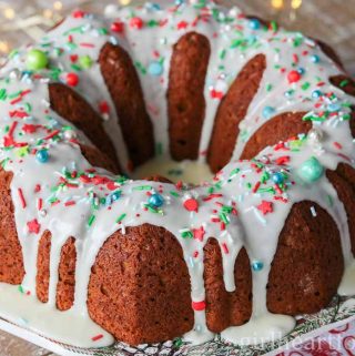 Gingerbread cake on a plate with icing sugar glaze and sprinkles.