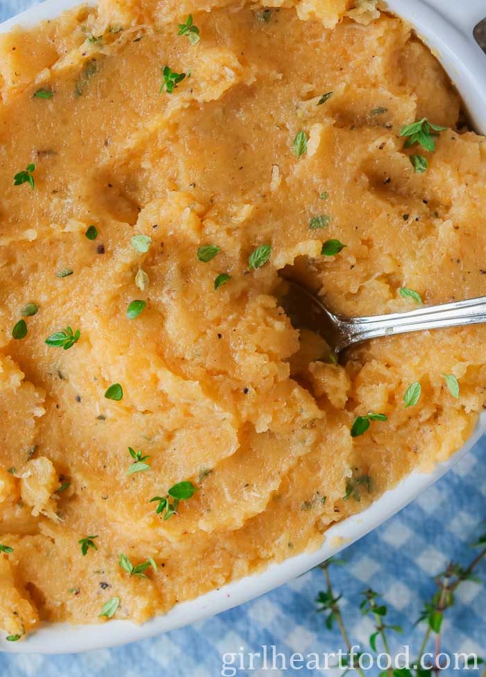 Close-up of mashed turnip in a dish with a spoon dunked into it.