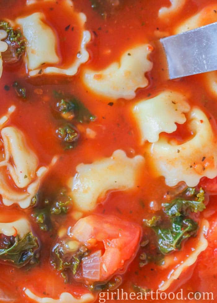 Tight close-up of tomato and tortellini soup.