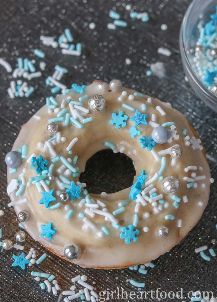 Glazed eggnog donut with sprinkles on a silver plate.