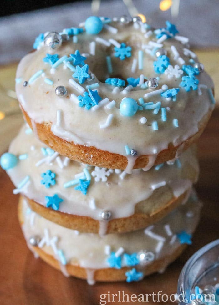Close-up of a stack of three glazed eggnog donuts with sprinkles.