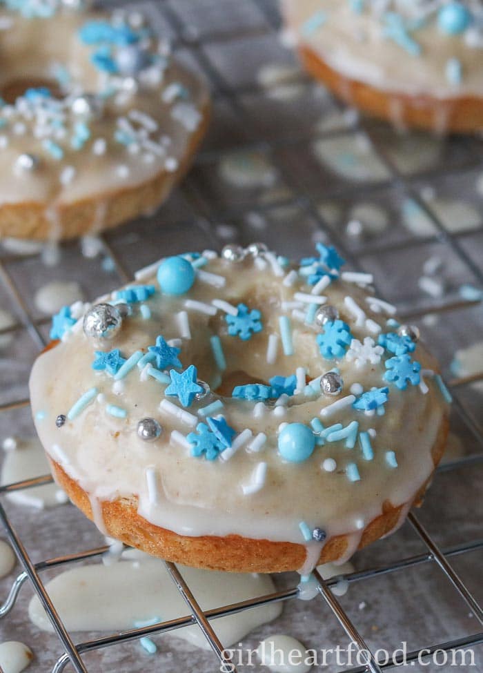 Glazed eggnog donut with sprinkles on a cooling rack.