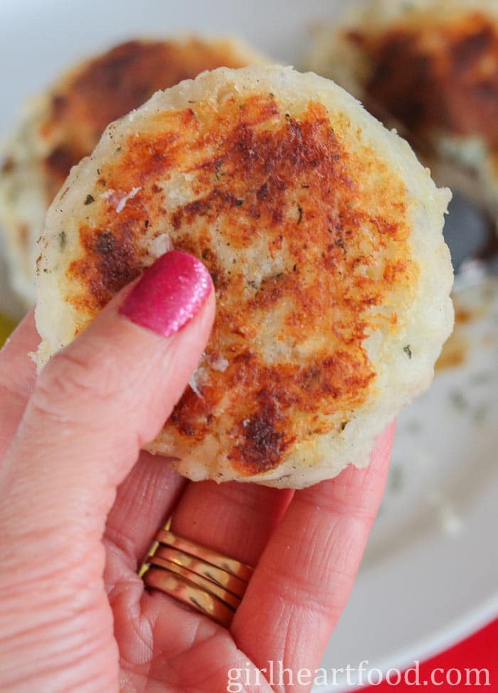 Hand holding a cooked salt cod fish cake.