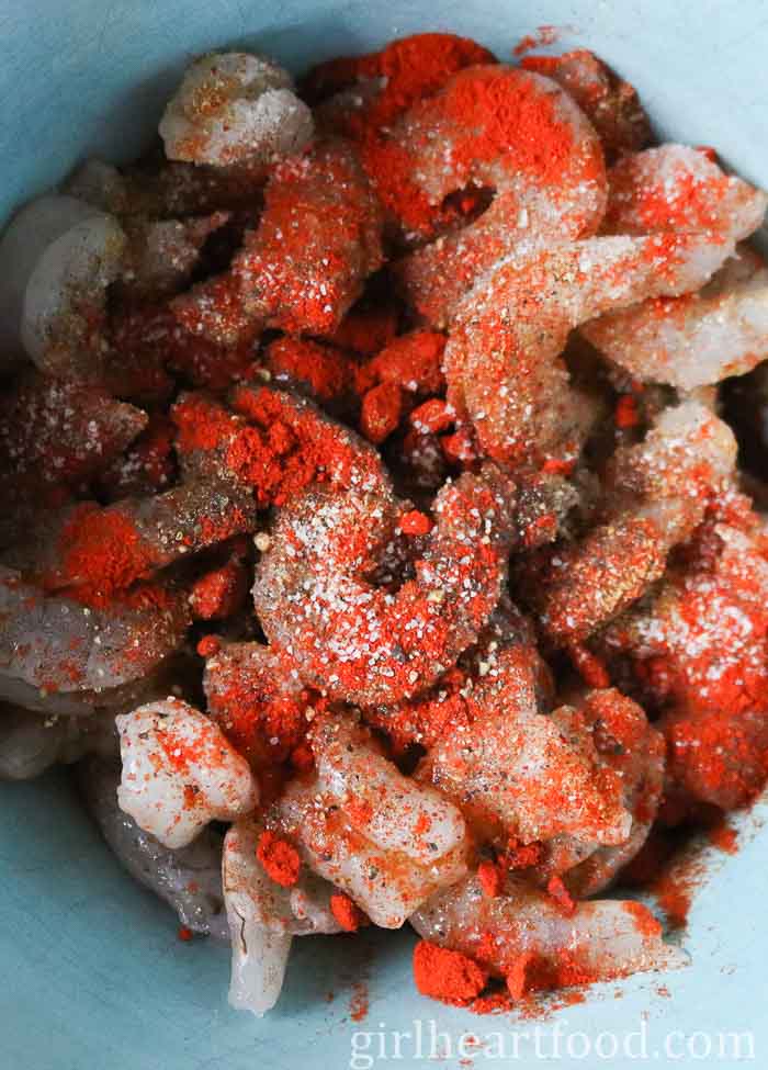 Seasoned raw shrimp in a blue bowl.