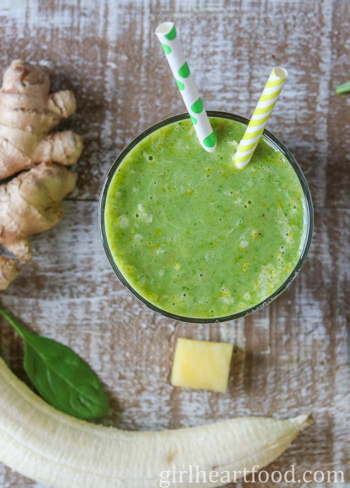 Overhead shot of a glass of ginger smoothie next to some smoothie ingredients.