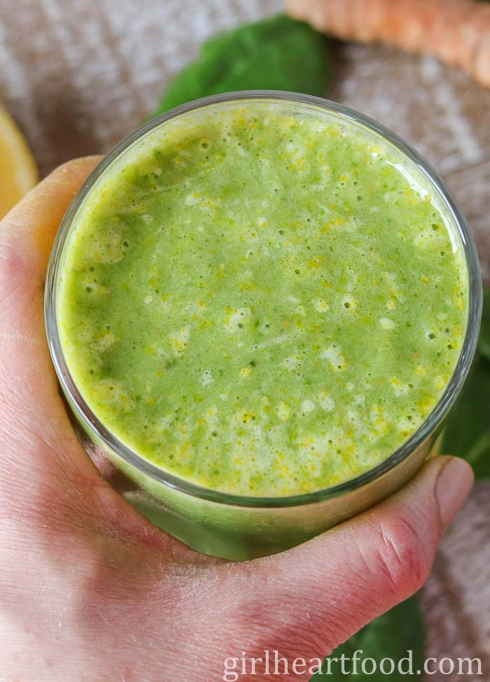 Hand holding a green smoothie.